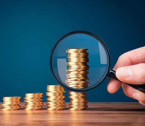 A magnifying glass inspects stacks of increasingly taller coins