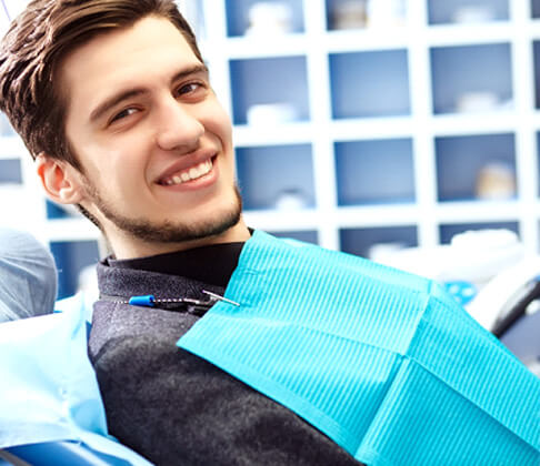 male dental patient sitting in chair and smiling